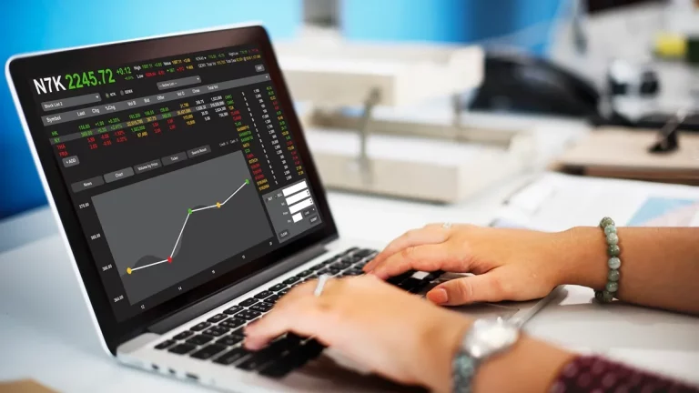Pessoa usando laptop com plataforma de negociação Forex exibindo gráficos e cotações do mercado financeiro