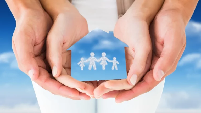 Mãos segurando uma figura em forma de casa com uma família representada no centro, simbolizando proteção e segurança familiar