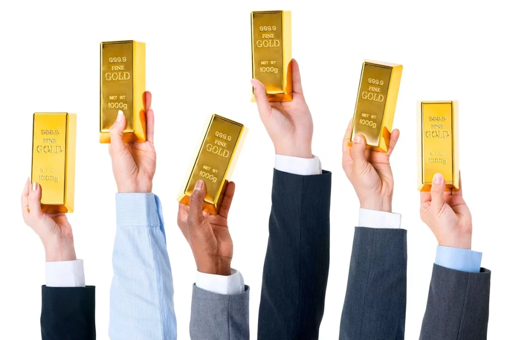 Várias mãos segurando barras de ouro brilhantes, representando investimento e riqueza.