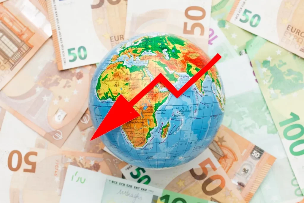Globo terrestre sobre cédulas de euro com seta vermelha apontando para baixo, simbolizando recessão econômica mundial.