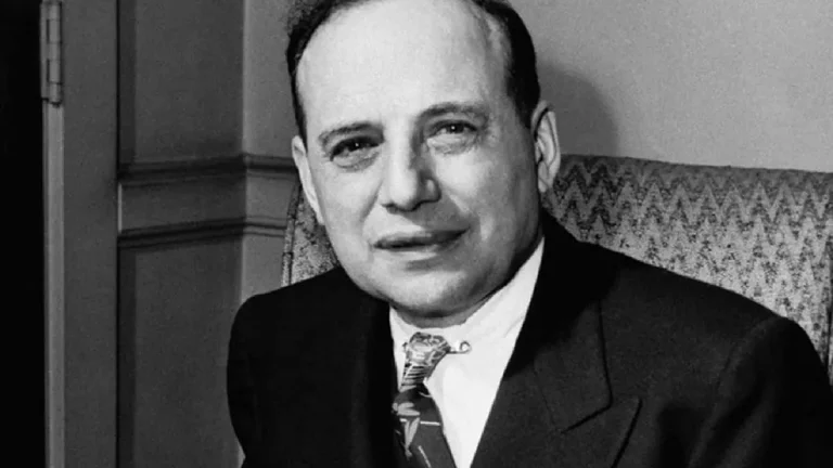 Retrato em preto e branco de Benjamin Graham, vestindo terno e gravata, sentado em poltrona com expressão serena.