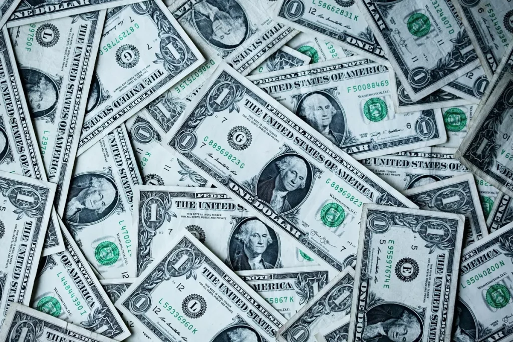 Várias notas de 1 dólar americano espalhadas em sobreposição, representando dinheiro em espécie, fluxo de caixa e operações financeiras em moeda estrangeira.