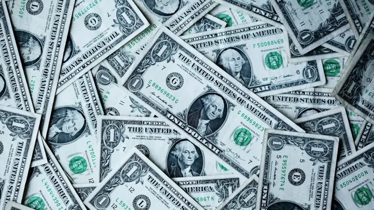 Várias notas de 1 dólar americano espalhadas em sobreposição, representando dinheiro em espécie, fluxo de caixa e operações financeiras em moeda estrangeira.