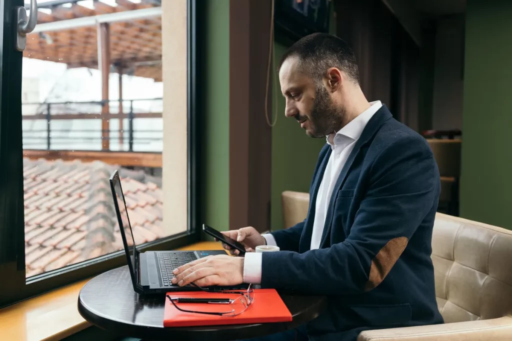 Homem de negócios usando notebook e celular em cafeteria