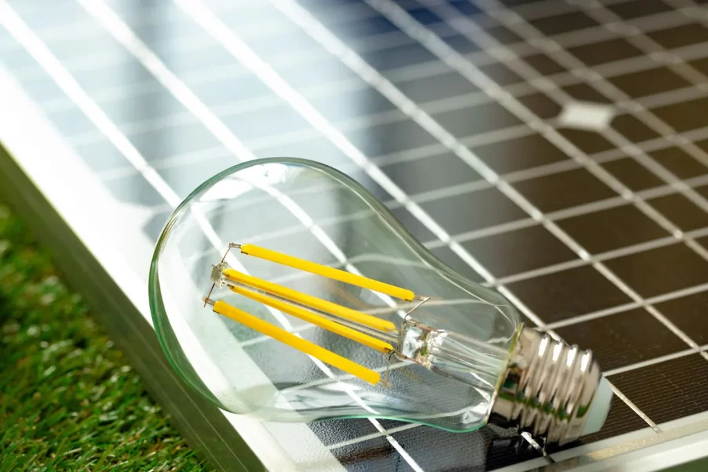 Lâmpada de LED sobre painel solar representando energia limpa e sustentável.