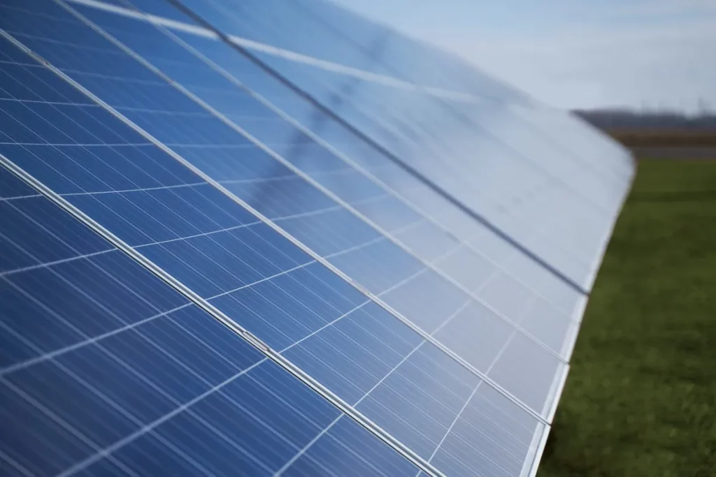 Painéis solares instalados em área verde com céu claro ao fundo.