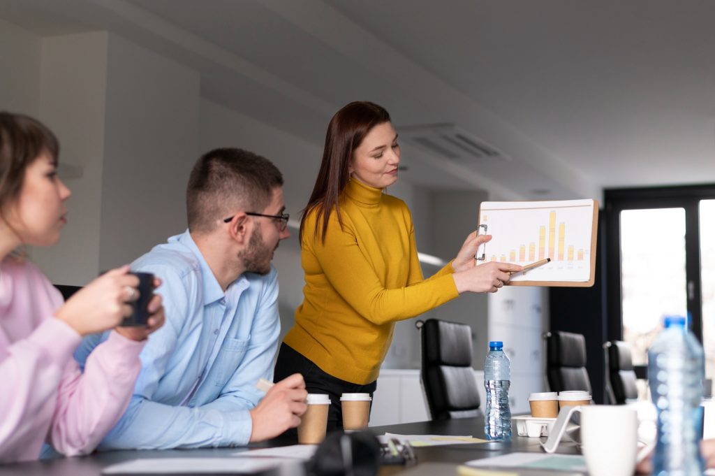 Mulher apresentando gráfico de crescimento para colegas durante reunião empresarial