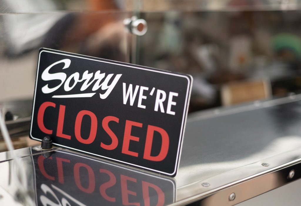 Placa com os dizeres "Sorry, we're closed", indicando fechamento de estabelecimento. Estabelecimento fechado com placa informativa