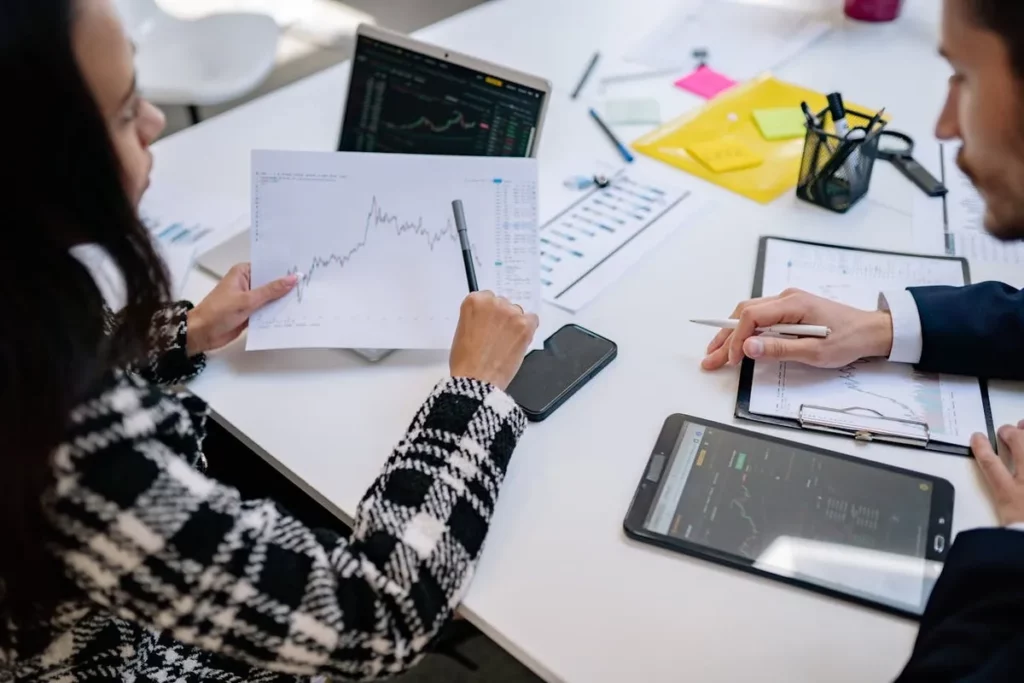 Profissionais financeiros analisando gráficos e dados de investimentos, discutindo estratégias para CDB para investir