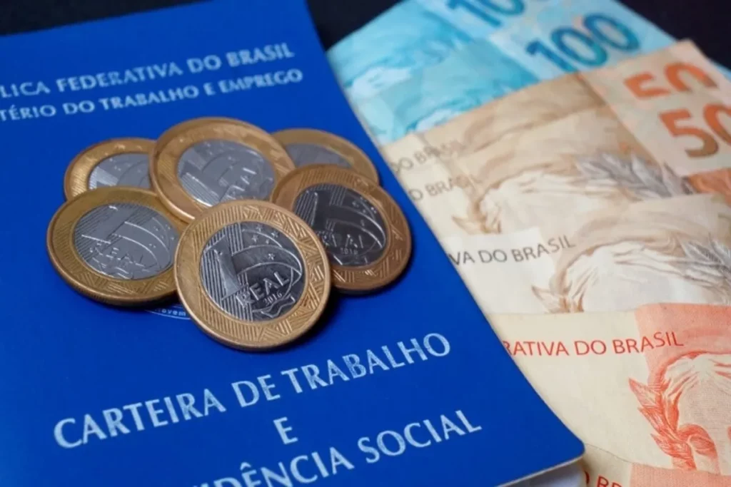 Seguro-desemprego, notas de dinheiro e moedas, carteira de trabalho, benefício financeiro.