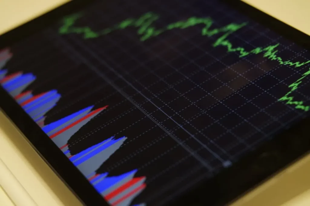 Uma tela de tablet mostrando um gráfico de ações com linhas verdes ascendentes e barras azuis e vermelhas, representando dados financeiros e o conceito de "stop loss" no mercado de investimentos.
