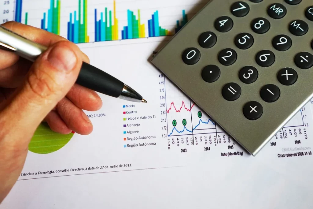 Pessoa analisando gráficos, com calculadora do lado