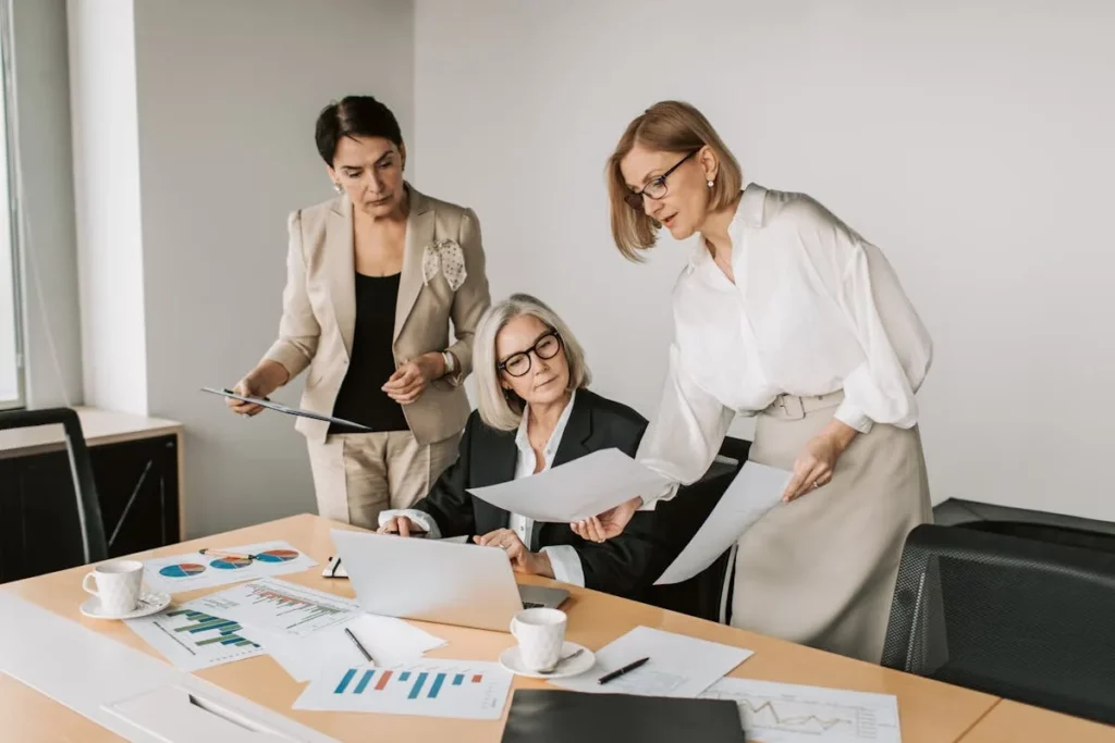 Pessoas analisando gráficos em folhas espalhadas sobre a mesa.