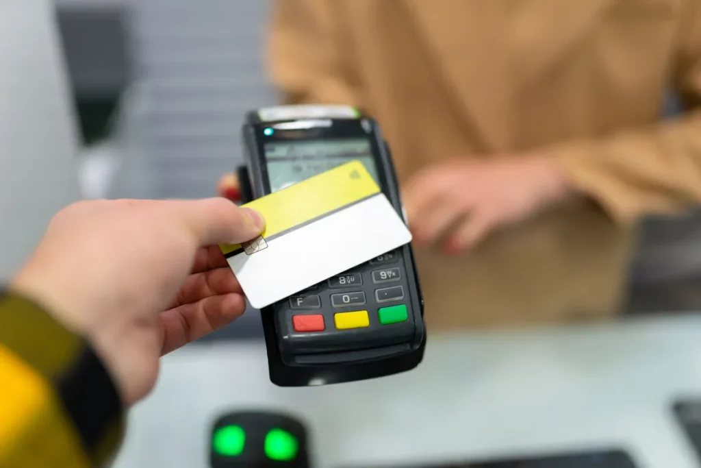 Cliente aproximando cartão de crédito de uma maquininha para realizar pagamento por aproximação.