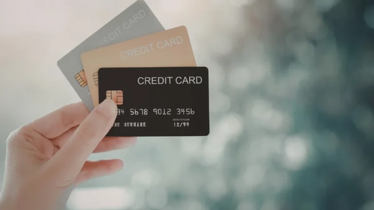 Pessoa segurando um cartão de crédito com a palavra “credit card” escrita na frente.