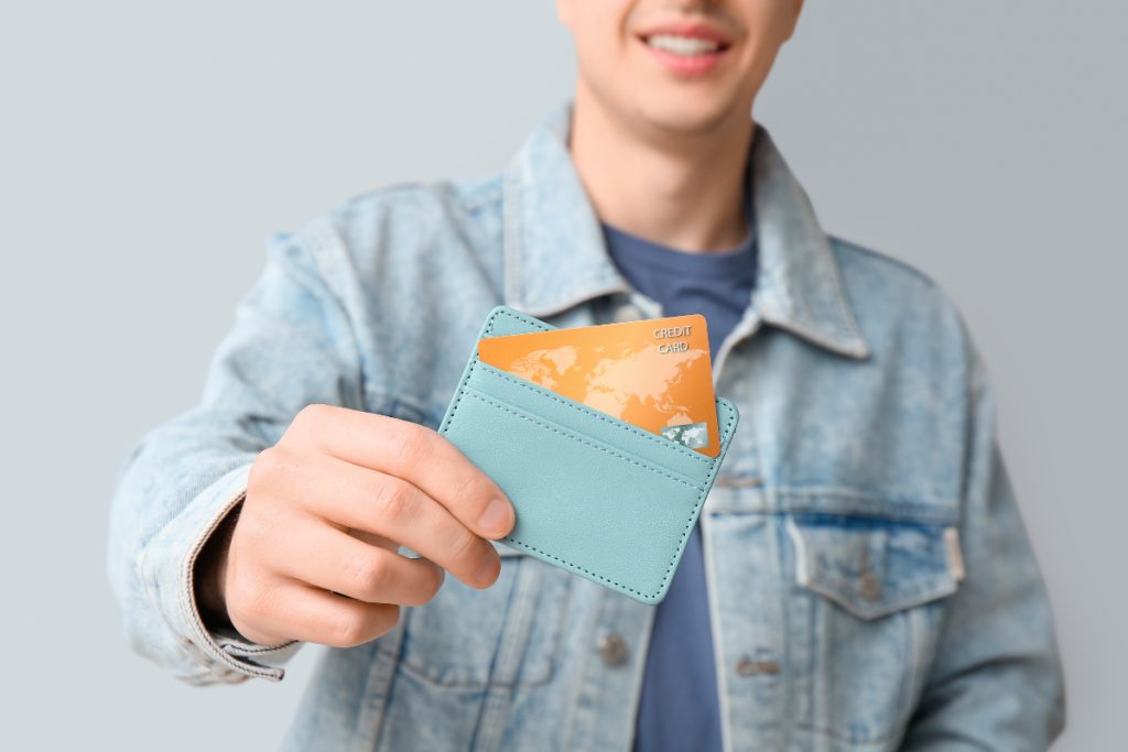 Pessoa segurando uma carteira com um cartão bancário parcialmente visível.