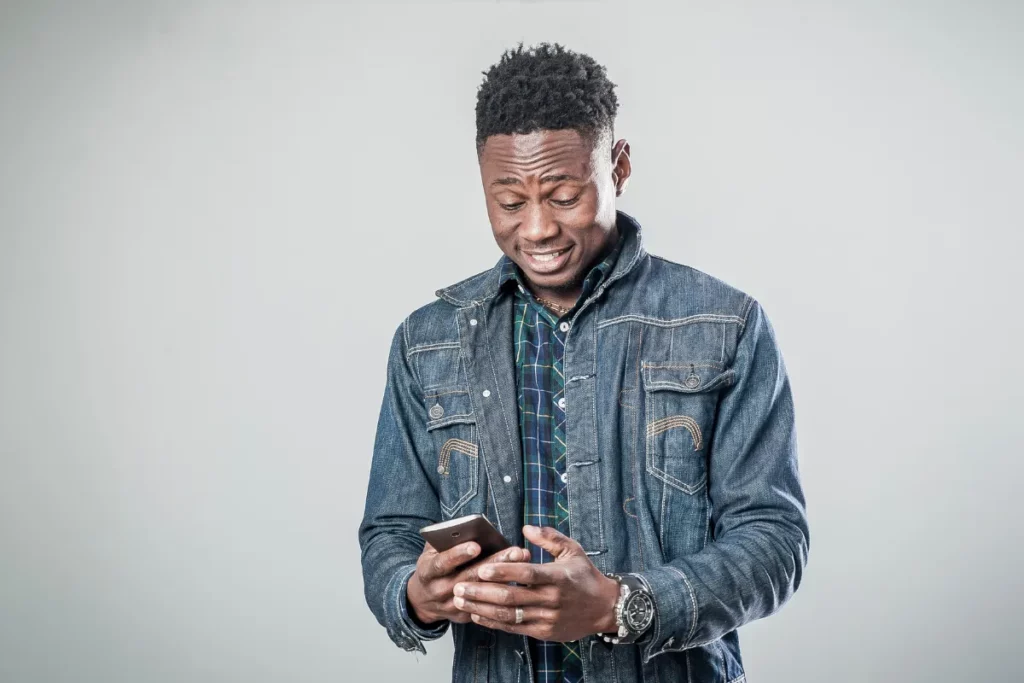 Homem segurando um smartphone e olhando para a tela enquanto utiliza um aplicativo no celular.