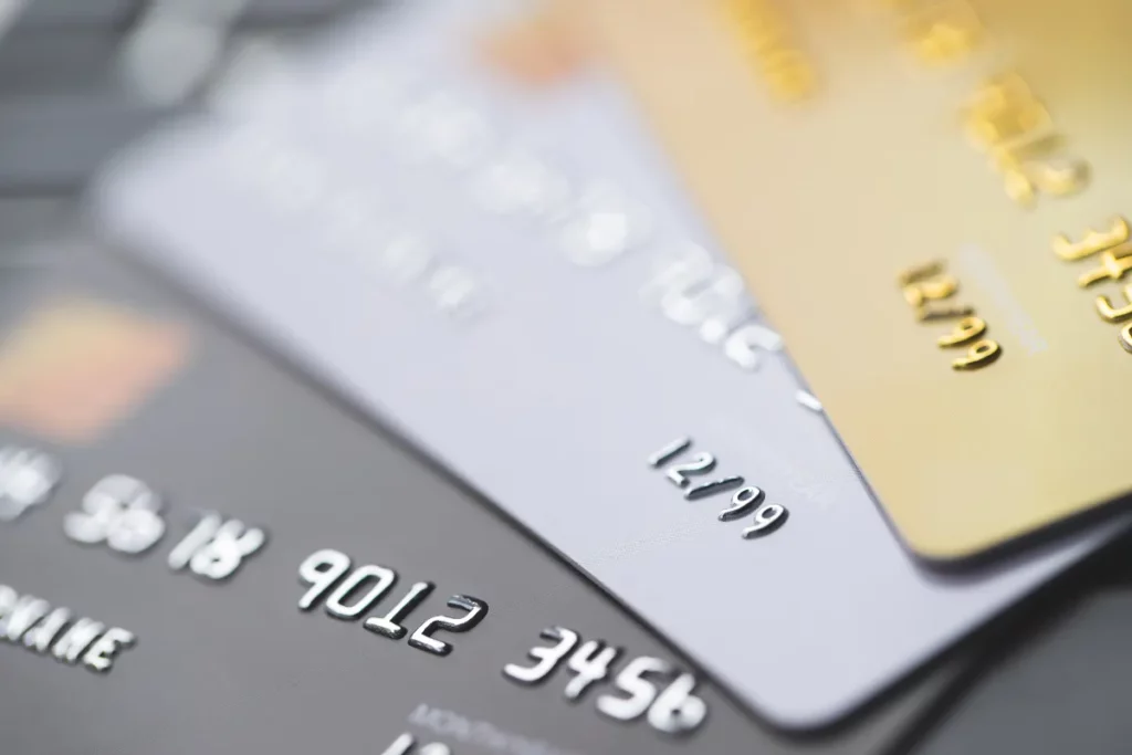 cartões de crédito sobrepostos com foco nos números e diferentes cores indicando bandeiras distintas