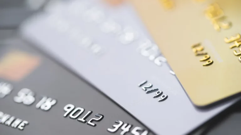 cartões de crédito sobrepostos com foco nos números e diferentes cores indicando bandeiras distintas